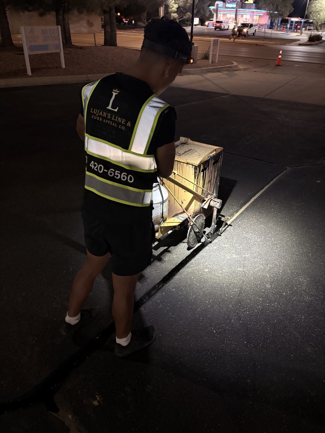 Nathaniel Lujan in a Lujan's Line branded reflective vest performing crack filling at night
