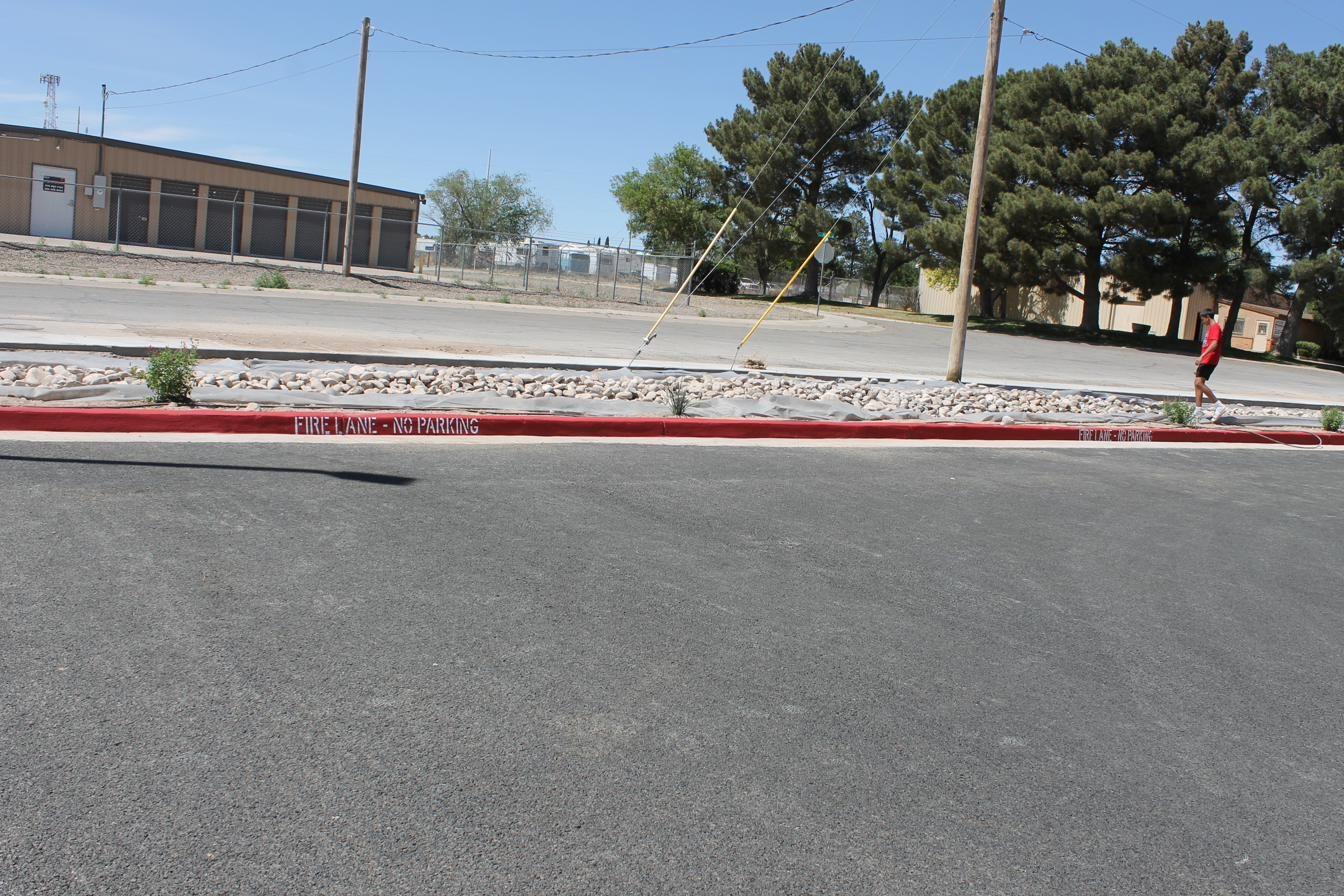 Bright red fire lane curb painting with FIRE LANE NO PARKING stencil